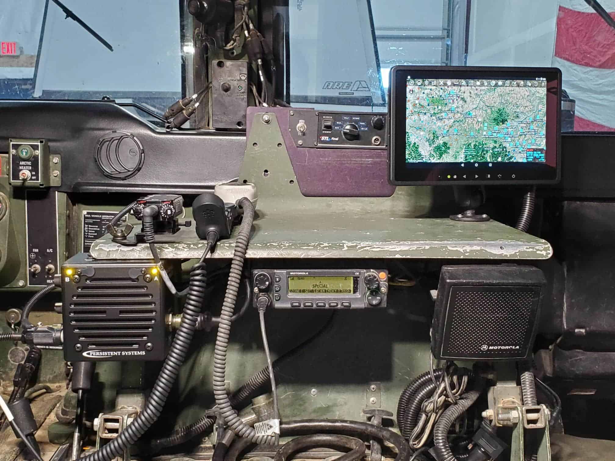 Cockpit workspace with multiple radios, cables, and a tablet showing a detailed map.